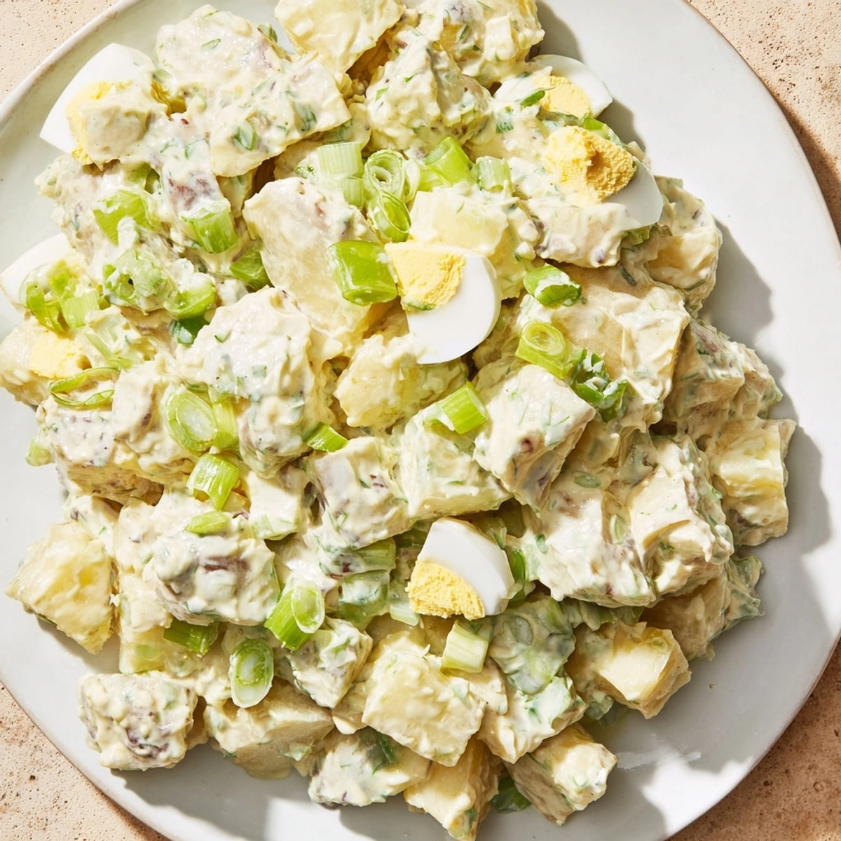 Freshly made potato salad with bright onion and egg—a comforting, classic side dish.