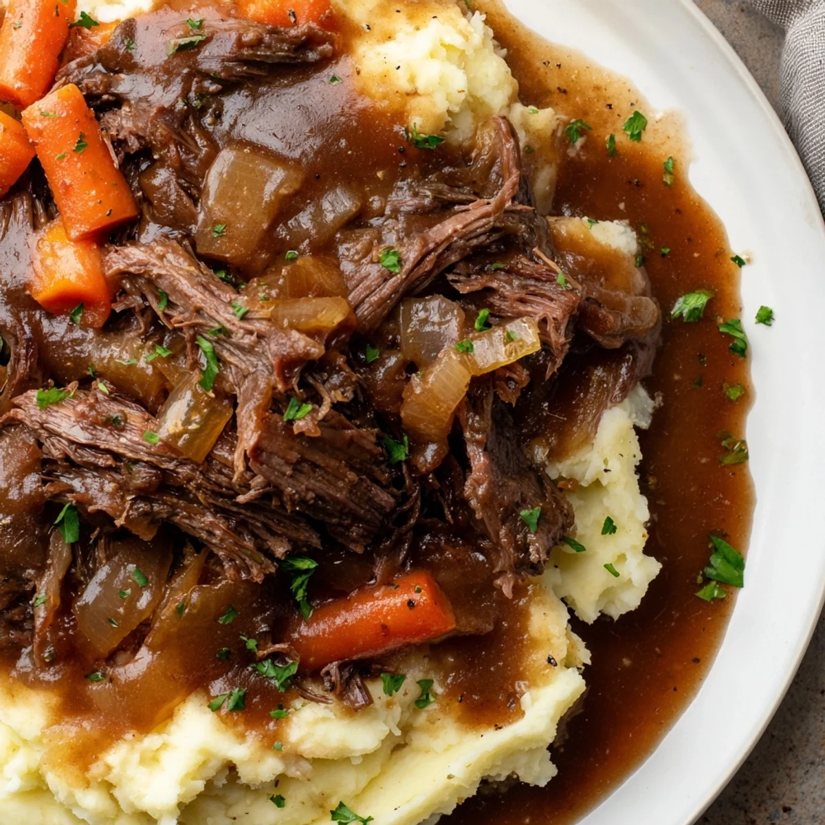 A flavorful serving of Slow Cooker Pot Roast, featuring juicy beef, aromatic vegetables, and creamy mashed potatoes.