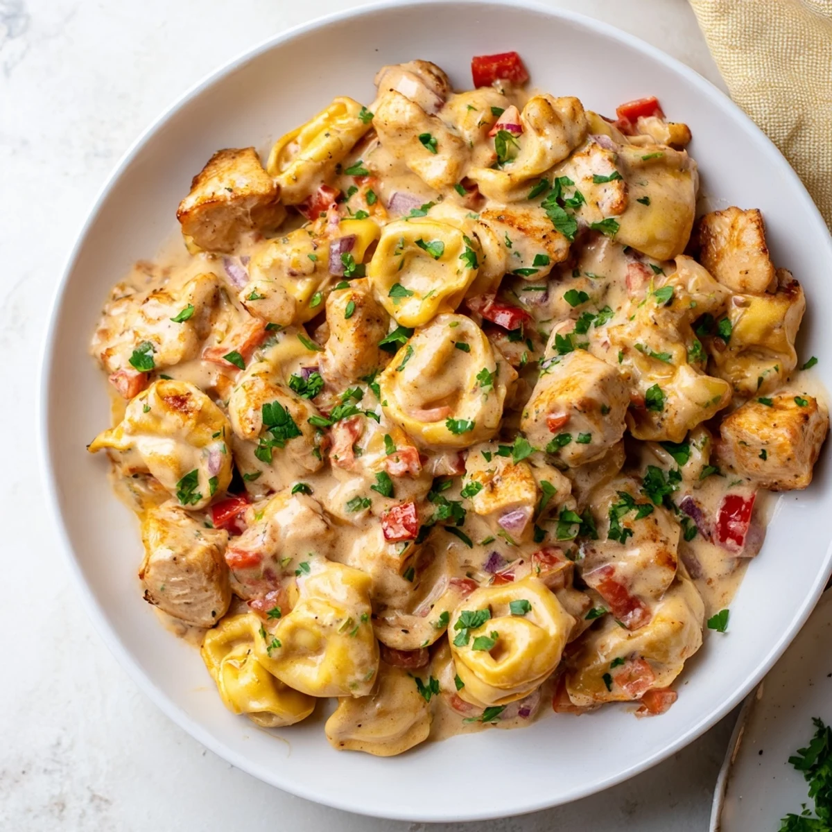 Golden, tender pieces of Zesty Cajun Garlic Parmesan Chicken Tortellini, served with fresh parsley garnish.