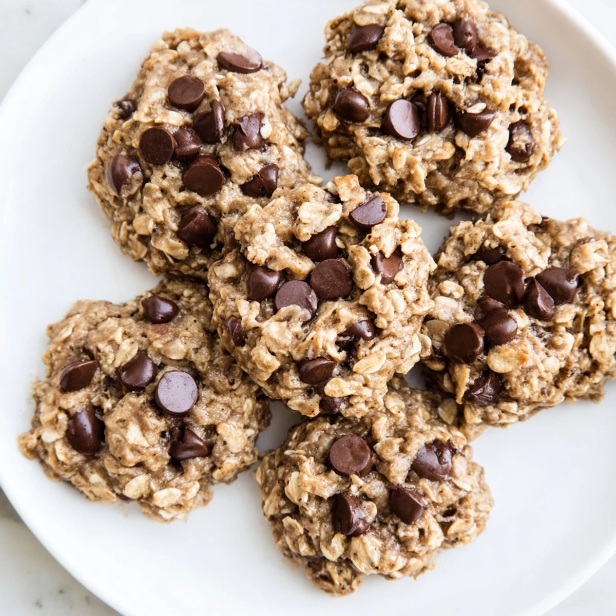 Close-up of baked Oat-Banana Chocolate Chip Cookies, showcasing melted chocolate chips and a soft texture.