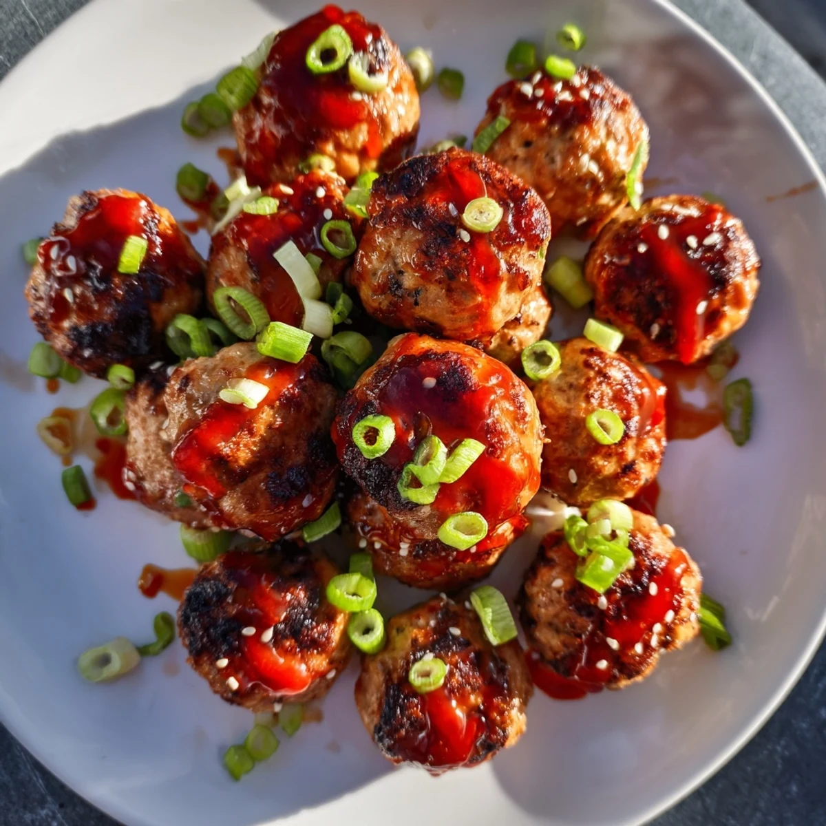 A plate of Spicy Honey-Glazed Chicken Meatballs, garnished with green onions, ready for a delicious meal.