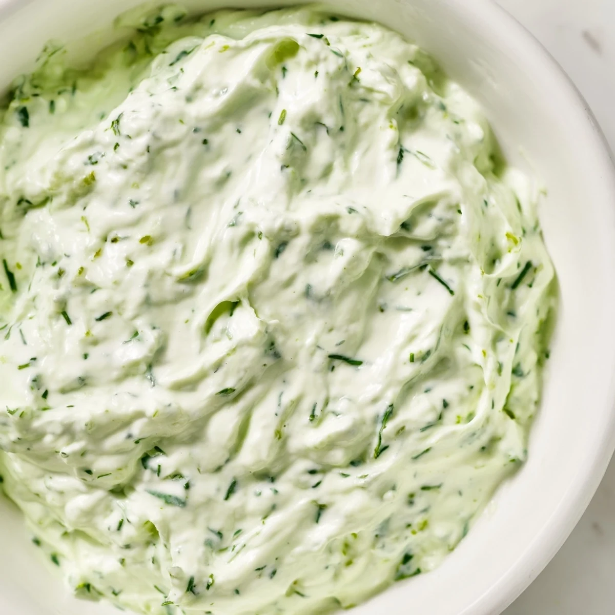 This Green Goddess Salad Dip is a creamy, herb-packed appetizer in a rustic bowl, surrounded by crisp tortilla chips and colorful vegetable sticks.