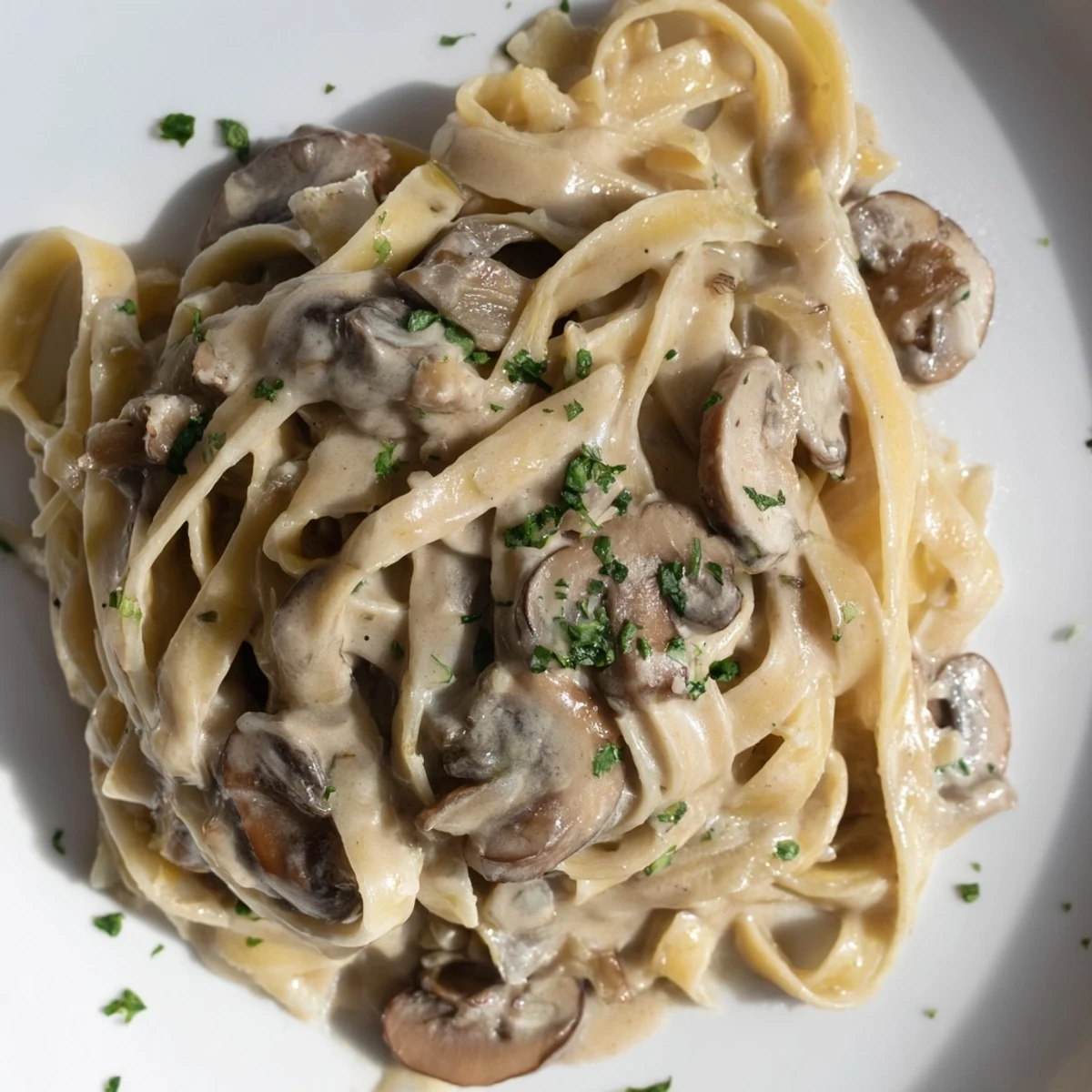 Steaming bowl of Creamy Mushroom Alfredo featuring tender fettuccine coated in a rich, velvety Parmesan sauce with mushrooms.