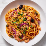 This pasta with tuna, olives, and capers boasts a vibrant tomato sauce and flaky tuna chunks awaiting.
