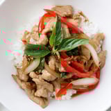 Steaming Thai Basil Chicken Bowls with fresh basil, tender chicken, and a savory sauce, ready to be enjoyed.