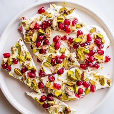 Vibrant frozen yogurt bark with pomegranate and pistachios, offering a healthy and sweet summer dessert.