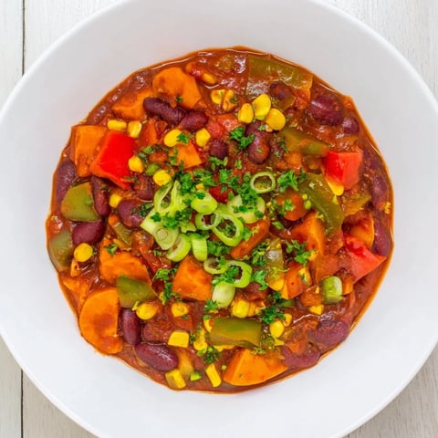 Steaming, rich Veggie Chili garnished with fresh cilantro, ready to serve with lime wedges.