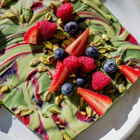 Creamy, swirled Frozen Yogurt Bark topped with vibrant berries and chopped pistachios, ready to enjoy.
