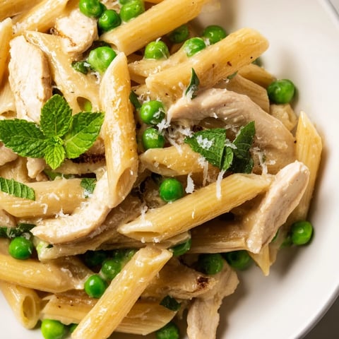 Tender chicken pieces and bright green peas mingle with al dente penne in a glossy lemon-herb sauce, garnished with fresh mint.  