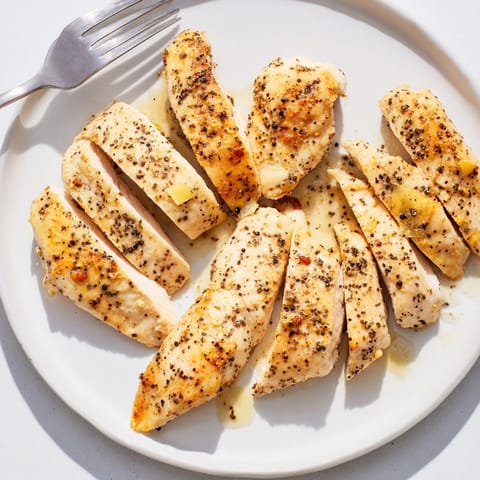 Plate of juicy Express Lemon Pepper Chicken next to vibrant green salad.