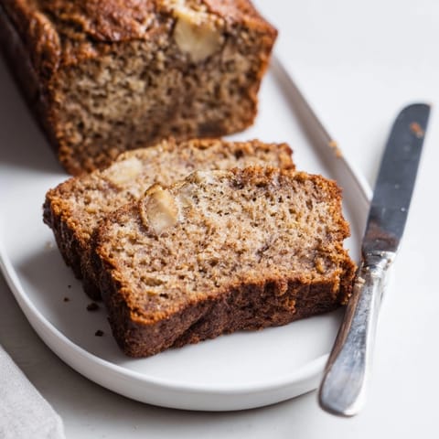 Slice of homemade banana bread with walnuts, perfect for breakfast or dessert.