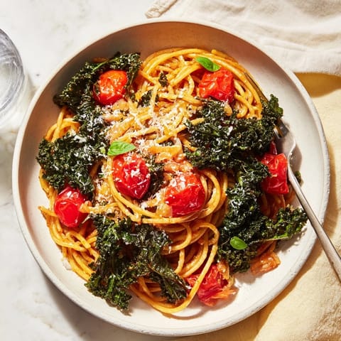 A close-up shot of the vibrant one-pot spaghetti, featuring tender kale and bright red tomatoes.