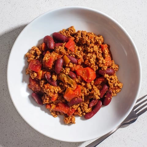 Garnished The Secret 4-Ingredient Chili steaming hot, alongside toppings like cheese and tangy sour cream.