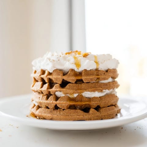 A delicious close-up showcases warm, spiced Express Gingerbread Waffle Stacks with fluffy whipped cream and syrup.