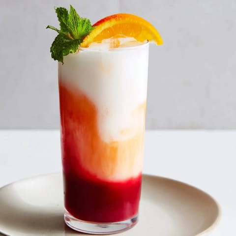 Refreshing Alpine Sunrise drink with an orange slice garnish, perfect for a sunny brunch celebration.