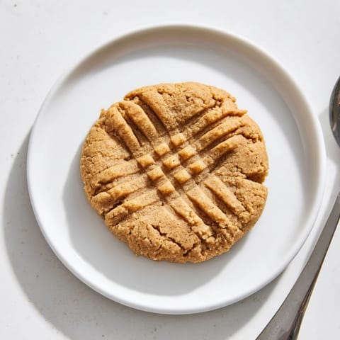 A plate of freshly baked flourless peanut butter cookies, with a crisscross fork pattern, ready to enjoy.