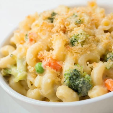 Hearty Garden Veg Mac and Cheese served from a baking dish, creamy cheddar sauce clinging to tender pasta and vegetables.