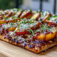Grilled flatbread topped with sweet BBQ peaches, melted Brie cheese, and fresh basil, perfect for summer gatherings.